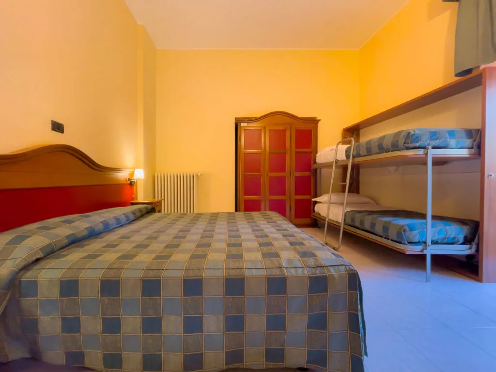 camera con letto matrimoniale e letto a castello accanto all'armadio in legno